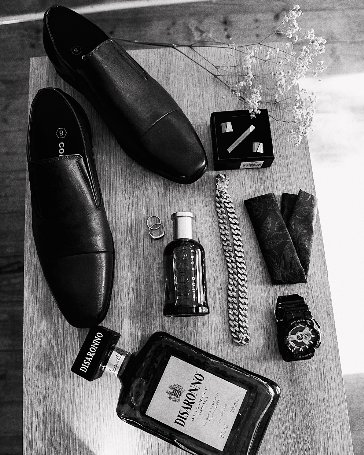 Flat lay of the groom's shoes, cologne, watch and rings